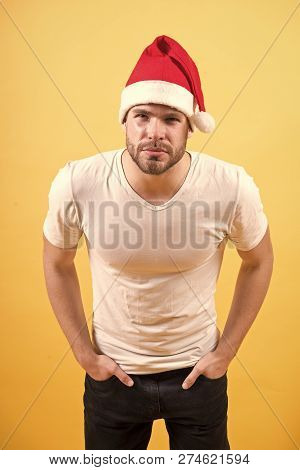 Guy Look With Squinty Eyes In Red Santa Hat And White Tshirt On Orange Background. Santa Claus Fashi