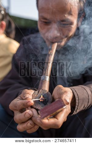 Meghalaya, India - May 12, 2017: Khasi man smoking traditional long pipe with tobacco