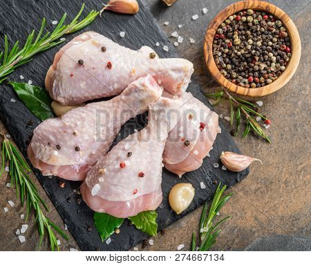 Chicken legs with spices and salt  ready for cooking on cutting board.