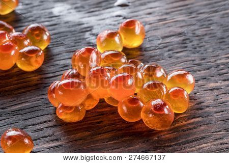 Several salmon roes on wooden background. Macro picture.