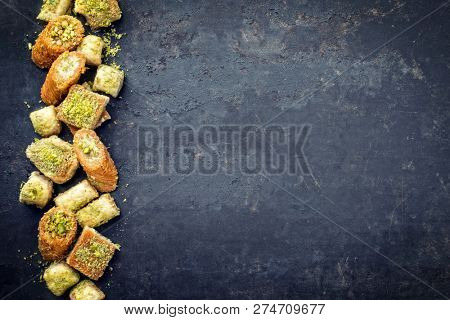 Traditional Oriental baklava collection as top view on a black board with copy space right 