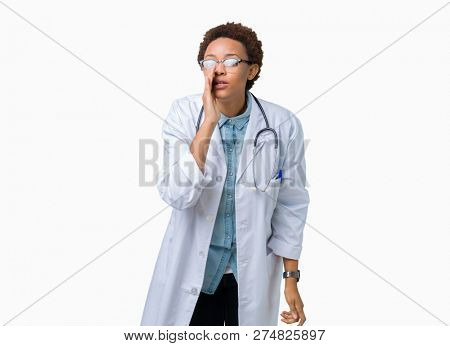 Young african american doctor woman wearing medical coat over isolated background hand on mouth telling secret rumor, whispering malicious talk conversation