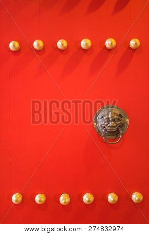 Red Wooden Door Of The Temple With The Brass Door Knocker