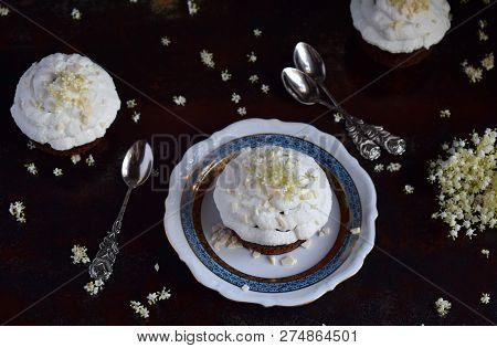 Chocolate Capcakes With Vanilla Cream Sprinkled With White Chocolate And Elderberry Flowers. Vintage