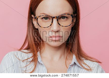 Close Up Shot Of Lovely Female Model Wears Big Optical Glasses, Has Brown Hair, Looks Seriously With