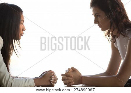 Women Sitting At Desk Staring At Each Other Unkindly