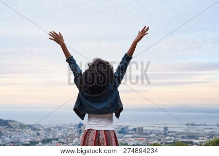 Backview of woman with arms raised, excited winning carefree