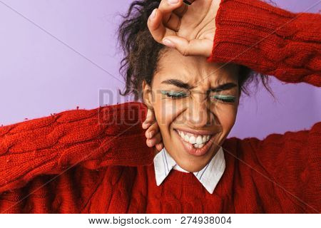 Portrait of uptight african american woman with afro hairstyle frowning and grabbing head isolated over yellow background