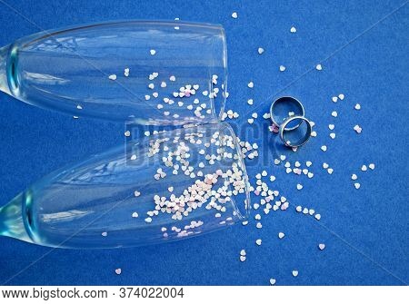 Heart Shaped Confetti Poured Glasses With Champagne On A Blue Background. Sequins And Silver Wedding