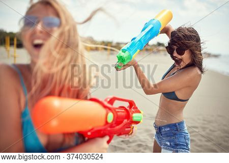 Crazy happy girl attacked her frinds  with water gun at beach at vacation.