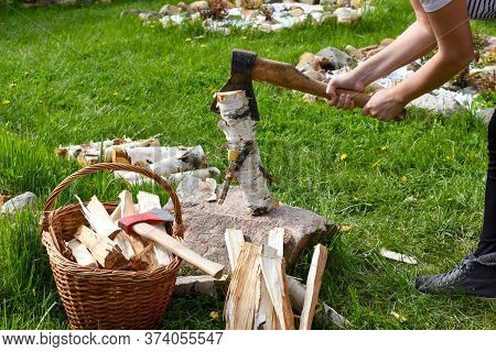 Woman Chopping A Log With An Ax In The Garden. Rural Life In The Summer. Chopping Firewood In The Fr