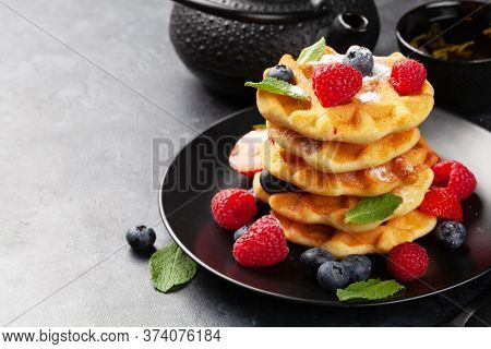 Delicious belgian waffles with ice cream and summer berries and breakfast tea. With copy space