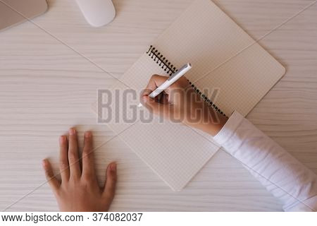 Top View Of Schoolboy Study At Desk In His Room. Boy Use Laptop And Smartphone To Writing In Noteboo
