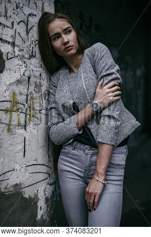 Girl In Grey Suit Posing Beside The Grey Wall