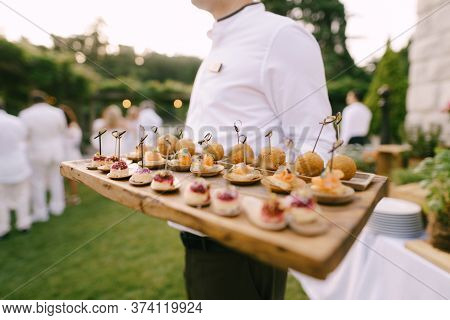 A Variety Of Canapees On A Wooden Board Passed Around By The Waiter