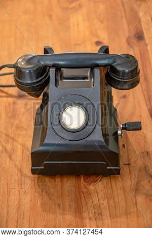 old back land line phone with a crank usually used in the army on a wooden table