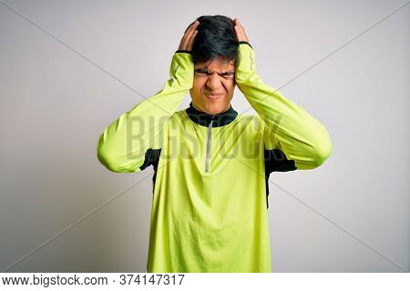 Young handsome sportsman doing sport wearing sportswear over isolated white background suffering from headache desperate and stressed because pain and migraine. Hands on head.