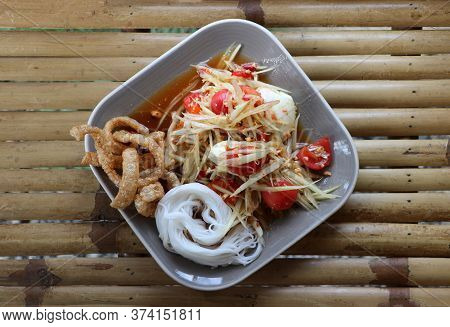 Green Papaya Salad With Salted Egg And Rice Noodles With Crispy Pork Skin In The Square Dish On The