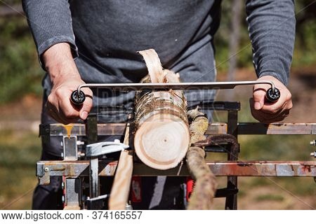 A Man Is Shaving An Wooden Log With An Drawknife