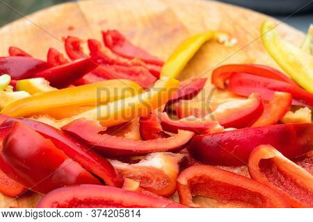 Slicing Red And Yellow Sweet Peppers On Wooden Cutting Board Close-up