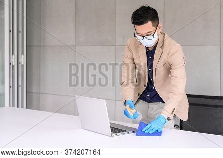 Businessman Wear Face Mask And Glove Using Microfiber Cloth And Alcohol Sanitizer Spray To Clean Lap
