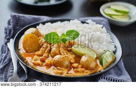 thai massaman curry on plate with jasmine rice and lime wedge