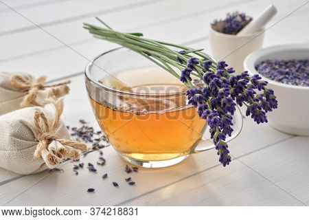 Cup Of Healthy Lavender Tea And Lavender Flowers. Mortars Of Dry Lavender And Sachets On Background.