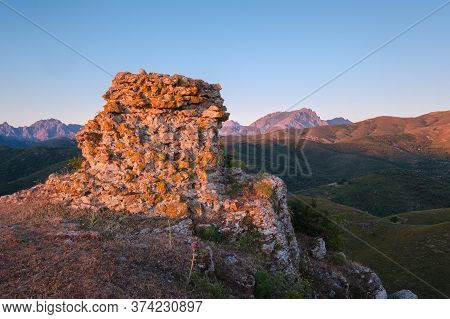 Early Morning Sun Lighting Up An Ancient Stone Wall In The Hills Of Corsica With The Mountain Of Mon