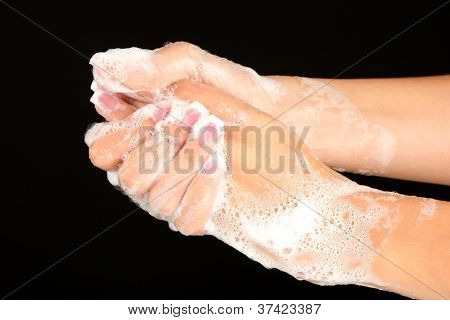 ผู้หญิงมือใน soapsuds บนพื้นหลังสีดำอย่างใกล้ชิด