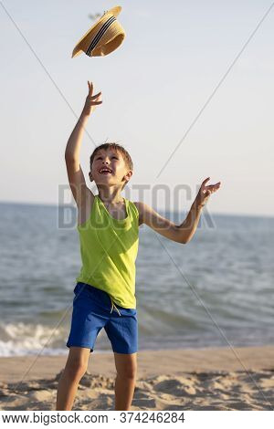 Happy Child At Sea. The Boy On The Coast Threw Up His Hat.