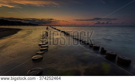 Sunset Landscape At The Sea. Wooden Breakwaters Line To The World War Ii Torpedo Platform At Baltic 