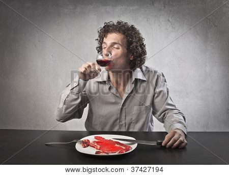 Uomo bere vino rosso e mangiare carne