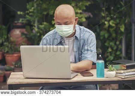 Businessman Wear Mask Working Online At The Home Office On The Laptop. Asian Young Entrepreneur Watc