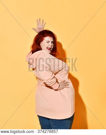 Side Shot Joking Positive Chubby Young Women Standing With Hands On Hips, Winking And Lolling, Wavin