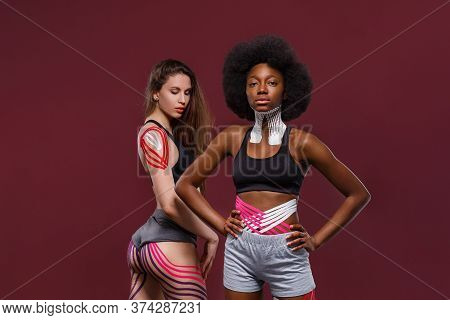 Kinesiology Taping. Two Young Female Athletes On Red Background With Kinesiology Tape On Neck, Shoul
