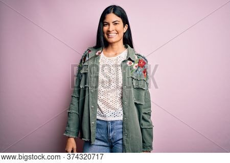 Young beautiful hispanic fashion woman wearing cool jacket over pink background with a happy and cool smile on face. Lucky person.