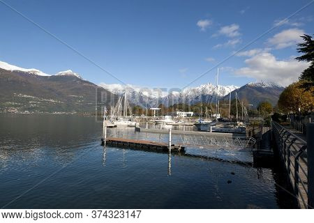 Colico, Italy, November 09, 2019 Colico Embankment Panoramic View With Ships And Mountains In Autumn
