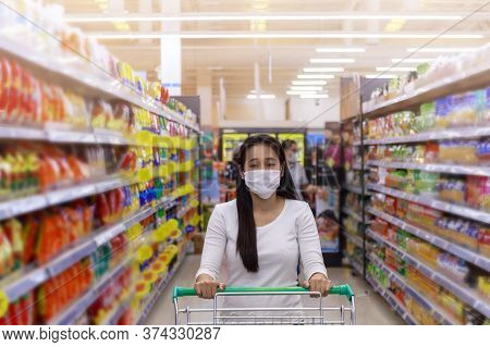 Asian Woman Wear Face Mask Push Shopping Cart In Suppermarket Departmentstore. Girl Choosing, Lookin