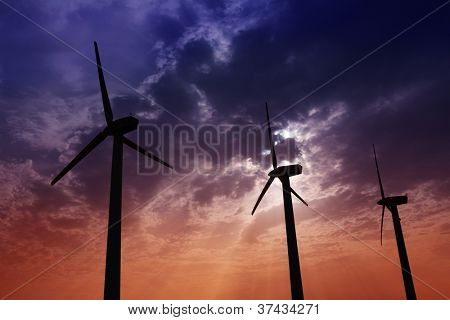 Aerogenerator mulini a vento in energia elettrica cielo drammatico tramonto verde