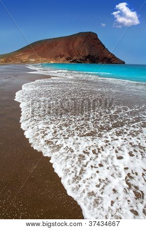 Stranden Playa de la Tejita turkis i Tenerife Kanariske øer med røde bjerg