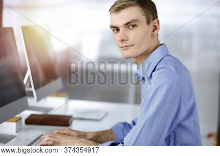 Young Successful Businessman Works With Computer, Sitting At The Desk In A Sunny Modern Office. Head