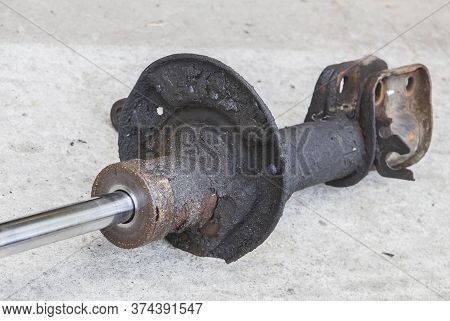 broken car shock absorber soiled with fuel oil on the concrete floor