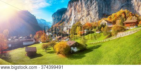 Stunning Autumn Landscape Of  Alpine Village Lauterbrunnen With Famous Church And Staubbach Waterfal