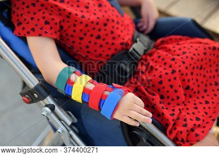 Little Disabled Girl Sitting In A Wheelchair. On Her Arms Orthosis. Child Cerebral Palsy. Inclusion.