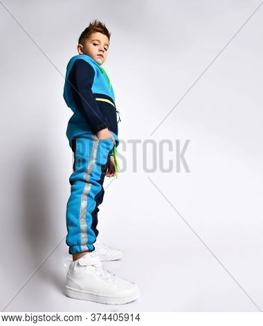 Side View Shot Of A Little Schoolboy In A Bright Cotton Tracksuit Standing With Hands In Pockets Loo