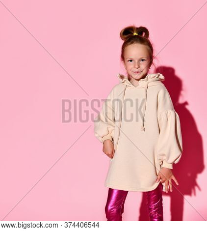 Cute Little Girl With An Updo Posing With Confident Look In Pale-pink Sweatshirt And Glossy Leggings