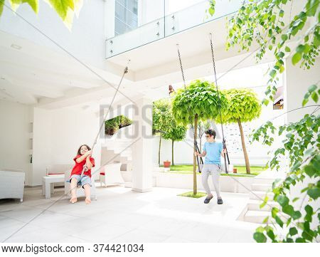 Two kids playing on the swing in a backyard of a villa