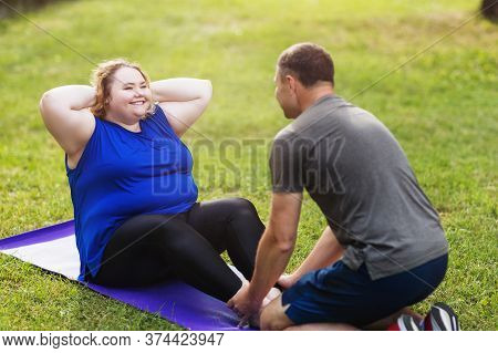 Young Blonde Size Plus, Performs An Outdoor Exercise With A Trainer. Concept On Healthy Lifestyle