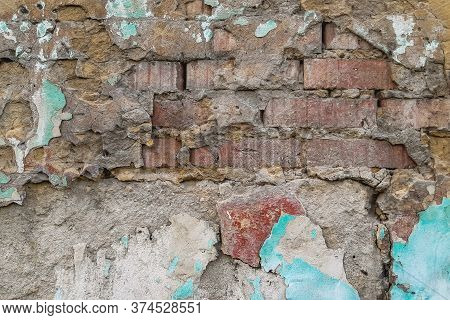 an old brick wall under a layer of broken plaster