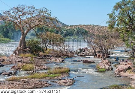 Epupa, Namibia - May 24, 2011: A Woman Washing Clothes In The Kunene River At The Top Of The Epupa W
